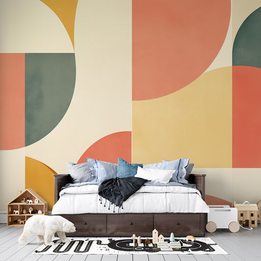Une chambre d’enfant avec un papier peint géométrique aux teintes douces de rose, jaune, vert et beige, créant une ambiance ludique et chaleureuse.