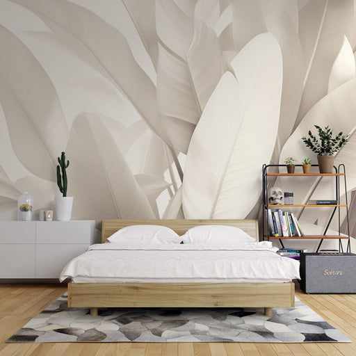 Une chambre apaisante avec un papier peint représentant de grandes feuilles blanches sur fond beige, créant une atmosphère douce et naturelle.