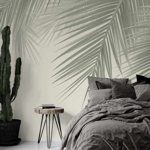 Une chambre apaisante avec un papier peint représentant de grandes feuilles de palmier dans des teintes vertes douces sur fond clair.