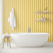 Une salle de bain lumineuse avec un papier peint à rayures jaunes et blanches créant une ambiance joyeuse et rafraîchissante.