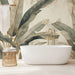 Une salle de bain élégante avec un papier peint tropical aux grandes feuilles vertes et dorées sur fond beige, créant une ambiance apaisante et naturelle.