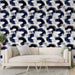Un salon moderne avec un papier peint abstrait bleu marine et blanc aux motifs ondulés créant une ambiance dynamique et artistique.