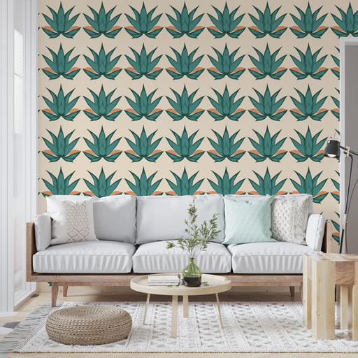 Un salon lumineux avec un papier peint représentant des feuilles d'agave vertes sur fond beige, créant une ambiance tropicale et rafraîchissante.