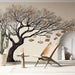 Une pièce lumineuse avec un papier peint illustrant un arbre stylisé aux branches nues, suspendant des livres colorés, créant une ambiance artistique et inspirante.