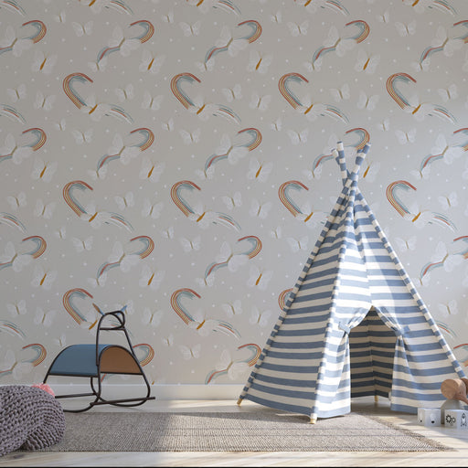 Une chambre d'enfant avec un papier peint ludique illustrant des arcs-en-ciel colorés et des papillons sur fond gris, créant une atmosphère joyeuse et rêveuse.