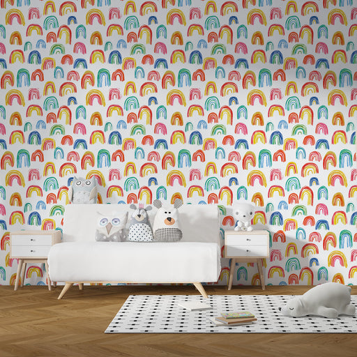 Une chambre d'enfant avec un papier peint joyeux représentant des arcs-en-ciel colorés sur fond blanc, créant une atmosphère ludique et chaleureuse.