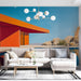 Un salon moderne avec un papier peint représentant une architecture colorée aux teintes orange et bleu, évoquant une ambiance artistique et contemporaine.