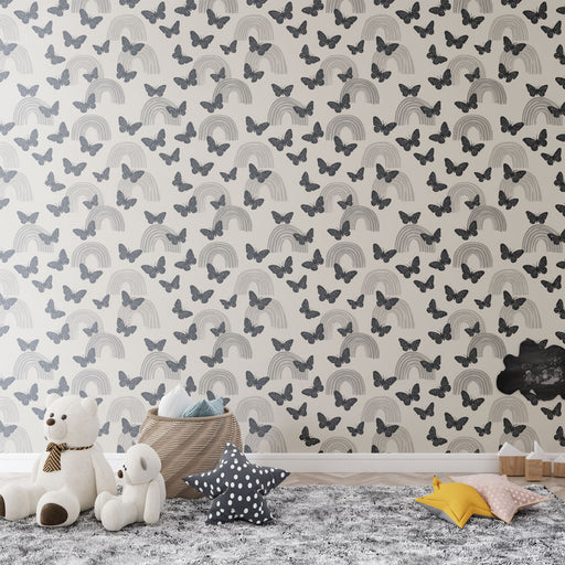 Une chambre d'enfant avec un papier peint illustrant des arcs-en-ciel et des papillons gris sur fond clair, créant une ambiance douce et rêveuse.