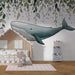 Une chambre d'enfant avec un papier peint illustrant une baleine stylisée flottant sous des feuilles délicates, créant une atmosphère ludique et apaisante.