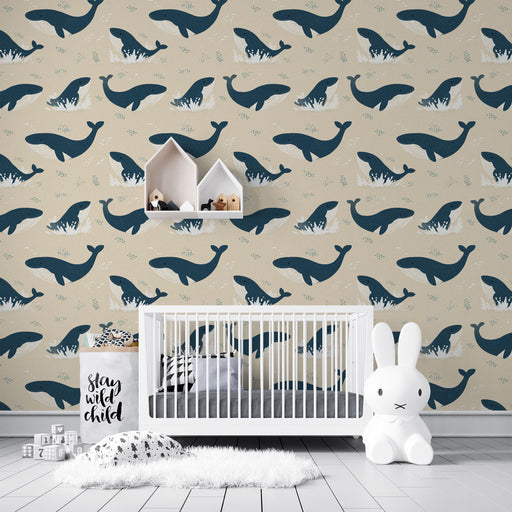 Une chambre d'enfant avec un papier peint illustré de baleines stylisées sur fond beige, créant une atmosphère ludique et apaisante.