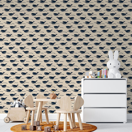 Une chambre d'enfant avec un papier peint beige orné de motifs de baleines bleues, créant une ambiance ludique et apaisante.
