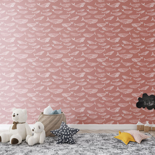 Une chambre d'enfant avec un papier peint rose orné de motifs de bateaux et de poissons blancs, créant une ambiance douce et ludique.