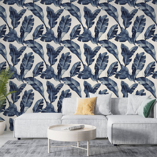 Un salon moderne avec un papier peint tropical bleu marine représentant de grandes feuilles sur fond clair, créant une ambiance fraîche et apaisante.