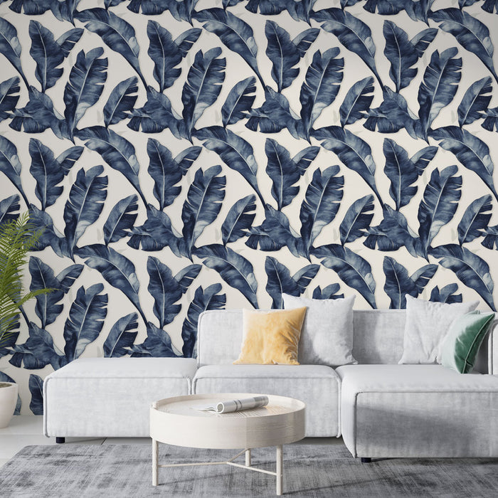 Un salon moderne avec un papier peint tropical bleu marine représentant de grandes feuilles sur fond clair, créant une ambiance fraîche et apaisante.