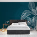 Une chambre moderne avec un papier peint bleu profond orné de feuilles blanches délicates, créant une atmosphère apaisante et élégante.