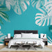 Une chambre moderne avec un papier peint tropical bleu vif orné de grandes feuilles de monstera, créant une atmosphère fraîche et vivante.