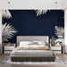 Une chambre moderne avec un papier peint tropical bleu nuit orné de grandes feuilles blanches, créant une ambiance élégante et apaisante.