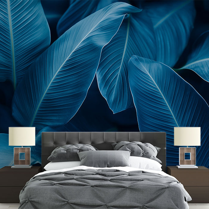 Une chambre moderne avec un papier peint représentant de grandes feuilles tropicales dans des teintes de bleu profond, créant une ambiance apaisante et élégante.