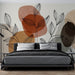 Une chambre moderne avec un papier peint aux motifs de feuilles stylisées en noir sur des formes abstraites dans des teintes chaudes, créant une ambiance chaleureuse et accueillante.