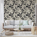 Un salon moderne avec un papier peint aux motifs de feuilles stylisées en noir et blanc sur fond beige, créant une atmosphère élégante et apaisante.
