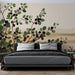 Une chambre moderne avec un papier peint botanique représentant des branches de feuillage vert et des baies noires sur fond beige, créant une atmosphère apaisante et naturelle.
