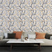 Un salon moderne avec un papier peint illustrant des branches noires ornées de feuilles dorées et de petits oiseaux sur fond clair, créant une atmosphère chaleureuse et accueillante.