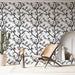 Une pièce moderne avec un papier peint noir et blanc représentant des branches fleuries, créant une atmosphère élégante et artistique.