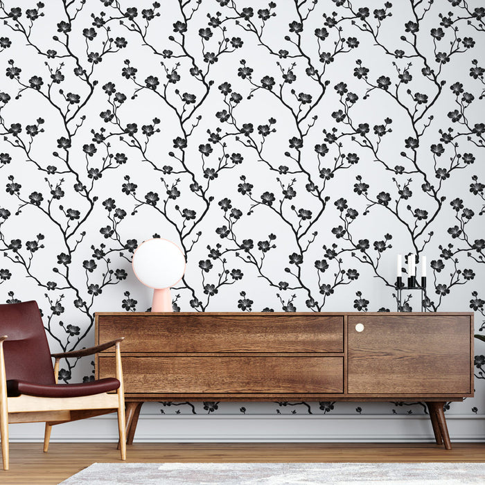 Un salon contemporain avec un papier peint floral noir et blanc représentant des branches délicates, créant une ambiance élégante et apaisante.