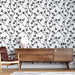 Un salon contemporain avec un papier peint floral noir et blanc représentant des branches délicates, créant une ambiance élégante et apaisante.
