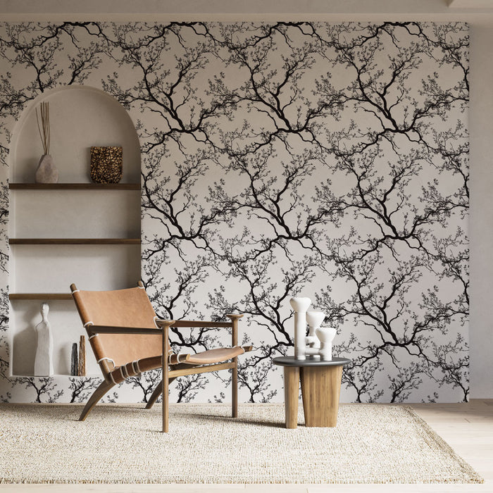 Un salon élégant avec un papier peint représentant des branches noires sur fond clair, créant une atmosphère artistique et apaisante.