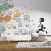 Une chambre d'enfant avec un papier peint ludique représentant des bulles colorées et un enfant en mouvement, créant une atmosphère joyeuse et dynamique.
