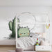Une chambre d'enfant avec un papier peint illustratif représentant un chat vert et un cactus, créant une ambiance ludique et joyeuse.
