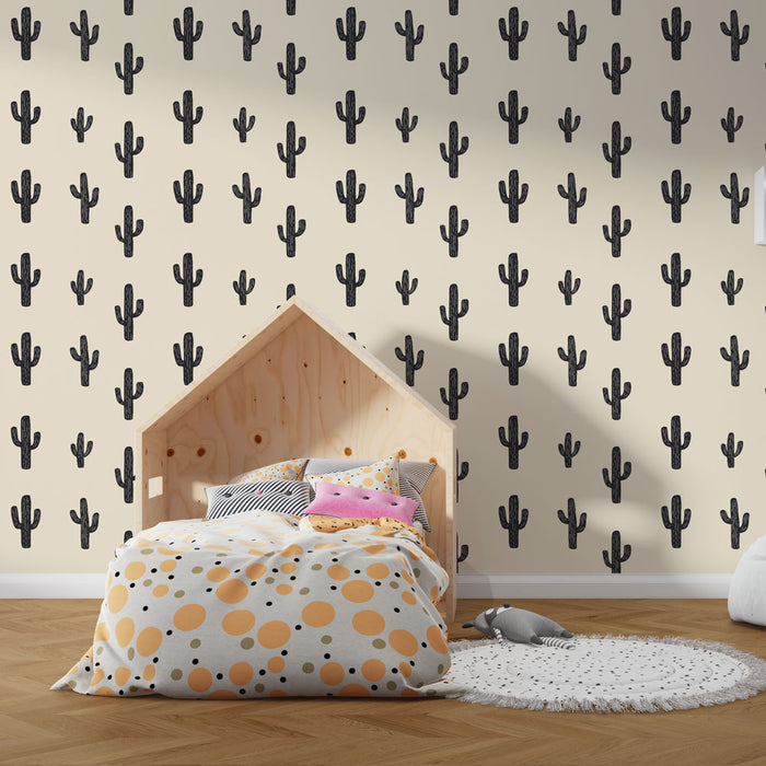 Une chambre enfantine avec un papier peint illustrant des cactus noirs sur fond crème, créant une ambiance ludique et moderne.