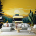 Un salon moderne avec un papier peint illustrant un camping-car devant un paysage montagneux au coucher de soleil, dégageant une ambiance chaleureuse et aventureuse.