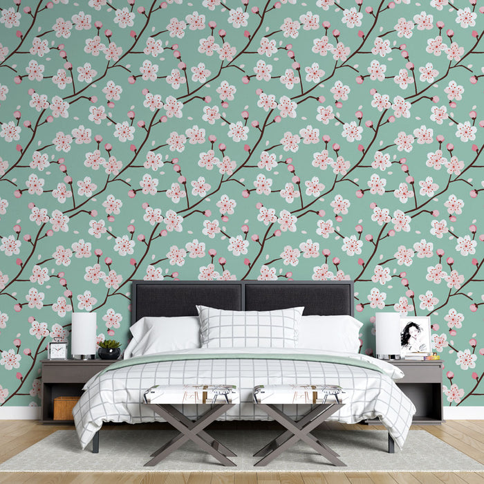 Une chambre lumineuse avec un papier peint floral vert d'eau orné de branches fleuries roses, créant une atmosphère douce et apaisante.