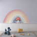 Une chambre d'enfant avec un papier peint ludique représentant un champignon sous un arc-en-ciel pastel sur fond violet, créant une ambiance joyeuse et imaginative.