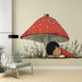 Une chambre enfantine avec un papier peint illustratif représentant un champignon rouge et un enfant endormi, créant une atmosphère douce et féerique.
