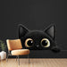 Une chambre moderne avec un papier peint représentant un adorable chat noir aux grands yeux, créant une ambiance ludique et chaleureuse.