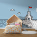 Une chambre d'enfant avec un papier peint illustratif bleu clair représentant un château de sable et des nuages, créant une ambiance ludique et estivale.