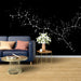 Un salon contemporain avec un papier peint noir orné de motifs étoilés et de branches blanches, créant une atmosphère cosmique et apaisante.