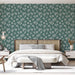 Une chambre moderne avec un papier peint vert profond orné de motifs de branches blanches, créant une atmosphère apaisante et naturelle.