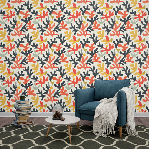 Un salon moderne avec un papier peint aux motifs coralliens colorés dans des teintes de rouge, noir et jaune, créant une ambiance dynamique et chaleureuse.