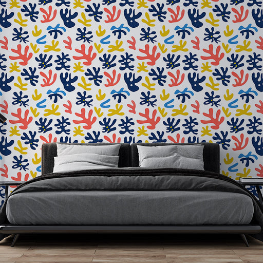 Une chambre moderne avec un papier peint coloré aux motifs abstraits de coraux en rouge, bleu et jaune sur fond blanc, créant une ambiance dynamique et joyeuse.