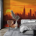 Une chambre moderne avec un papier peint représentant un panorama urbain au coucher de soleil, dégradé d'orange et de rouge, créant une atmosphère chaleureuse et dynamique.