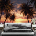 Une chambre moderne avec un papier peint tropical représentant des palmiers silhouettés au coucher de soleil, créant une atmosphère relaxante et chaleureuse.