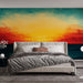 Une chambre moderne avec un papier peint représentant un coucher de soleil vibrant aux nuances orange, jaune et turquoise, créant une ambiance chaleureuse et apaisante.