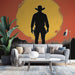 Un salon contemporain avec un papier peint illustrant la silhouette d'un cowboy devant un grand soleil jaune sur fond rouge, créant une ambiance western audacieuse.