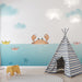 Une chambre d'enfant avec un papier peint ludique représentant un crabe souriant émergeant d'une mer turquoise, entouré de bateaux en papier colorés.