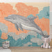 Une chambre d'enfant avec un papier peint illustrant un dauphin stylisé dans des vagues colorées, créant une ambiance ludique et marine.