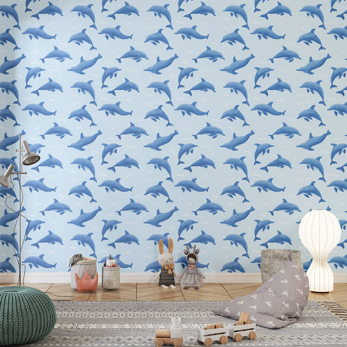 Une chambre d'enfant avec un papier peint illustrant des dauphins bleus sur fond bleu clair, créant une ambiance ludique et marine.